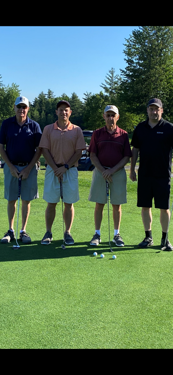 A group of men standing on a golf course

Description automatically generated with low confidence