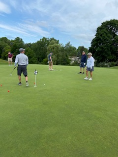 A group of people playing golf

Description automatically generated