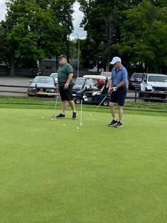 Two men playing golf on a green field

Description automatically generated with low confidence