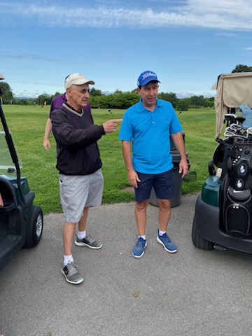 Two men standing next to golf carts

Description automatically generated with medium confidence