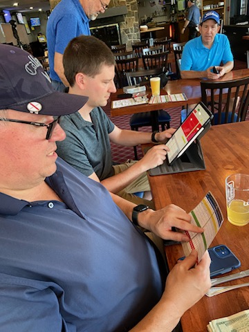A group of men sitting at a table looking at a menu

Description automatically generated with medium confidence